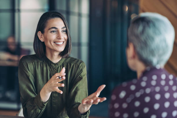 two businesswomen talking in the office - commerciaux photos et images de collection